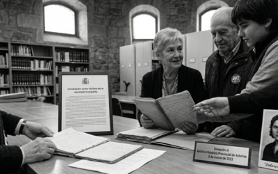 Fotografía en blanco y negro que ilustra la donación de las memorias de Dolores Valdés al Archivo Histórico de Asturias, mostrando a personas mayores y a una joven juntas alrededor de los documentos originales y una foto simulada de Dolores en 1938.